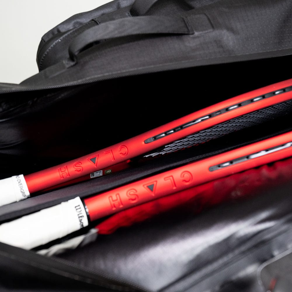 Two red tennis rackets are partially visible inside an open Cancha Original Racquet Bag (25L) made from lightweight, water-repellent materials.